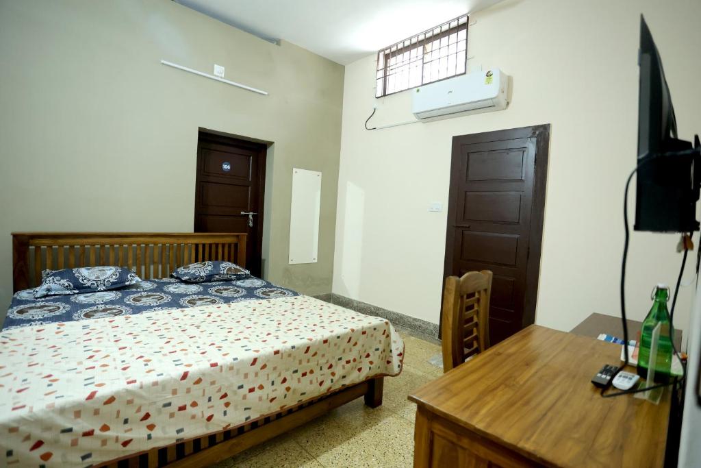 a bedroom with a bed and a desk and a television at Devaki Tourist Home in Ambalapulai