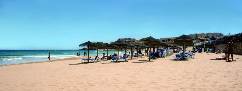 una playa con sillas y sombrillas y el océano en Apartamento La Mata, en La Mata