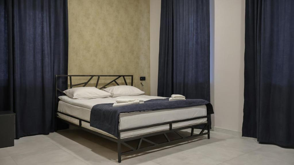a bed in a room with blue curtains and a bedvisor at Old Well Hotel in Tsaghkadzor