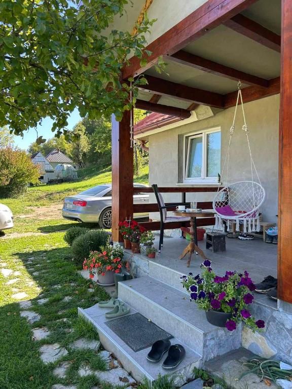 a porch of a house with a bench and flowers at Topli Kutak in Blatina