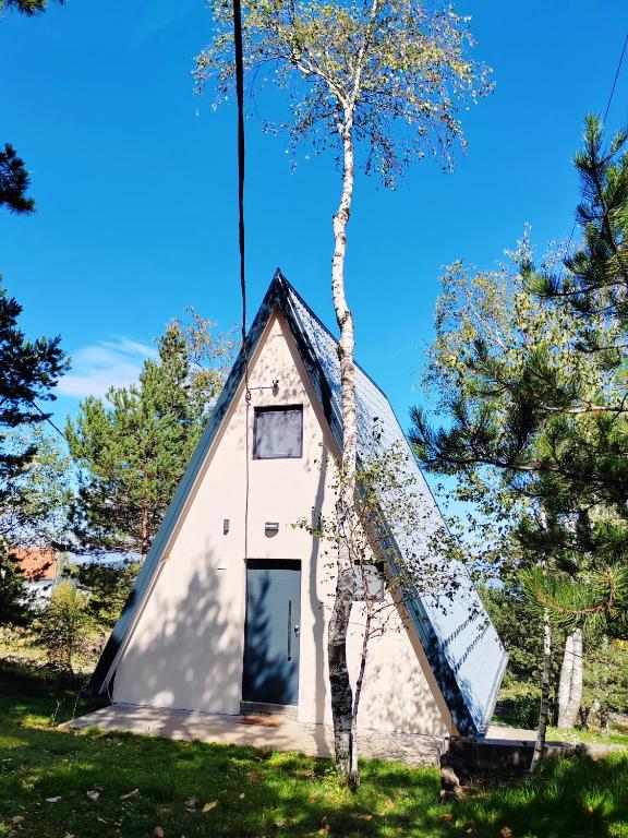 a small white triangular house with a tree at A frame Simić in Divčibare