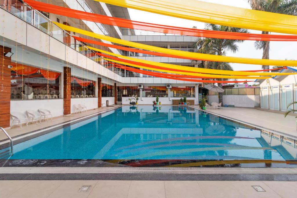a large swimming pool in a building with orange and yellow overhead at Treebo Arya Palace With Swimming Pool in Dehradun