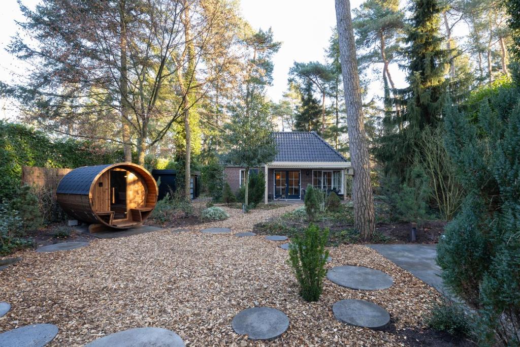 a garden with a wooden tub in front of a house at Lodge met eigen wellness onder de bomen in Lochem