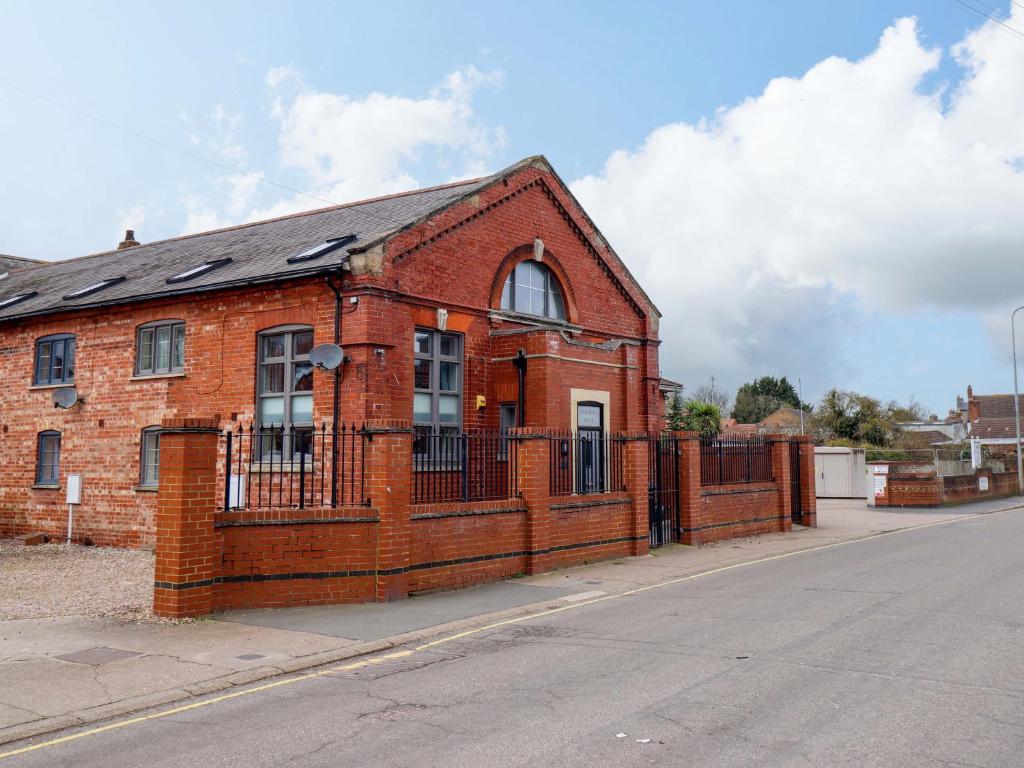 a red brick building with a fence on a street at 3 The Old Drill Hall in Alford