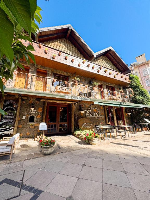 a building with tables and chairs in front of it at Hotel Giardino Di Pietra in Gramado