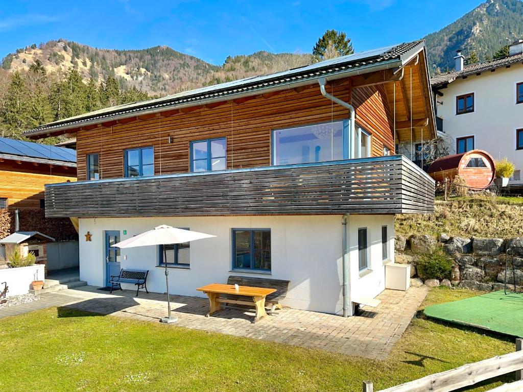a house with a table and an umbrella in a yard at Ein Haus am Berg in Marquartstein