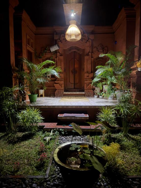a courtyard with a door and a pond with plants at Rahayu House in Kusamba