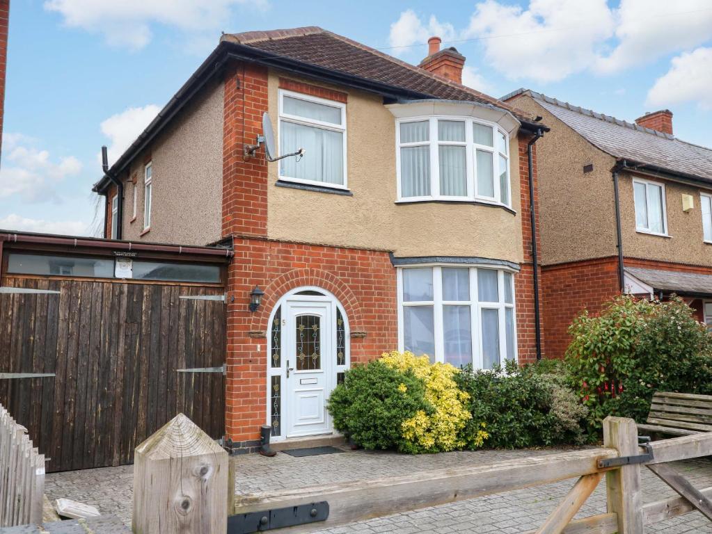 a brick house with a white door and a fence at 5 Wallace Road in Loughborough