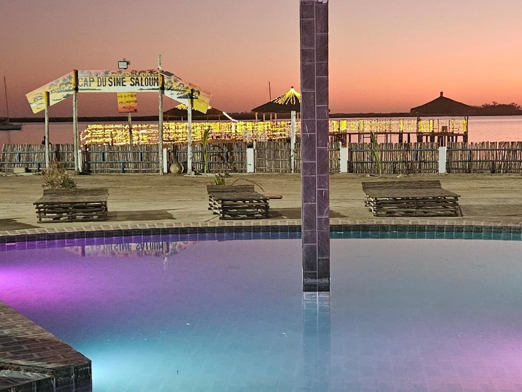 a pool in front of a pier at sunset at Hotel Cap du Sine Saloum in Ndangane