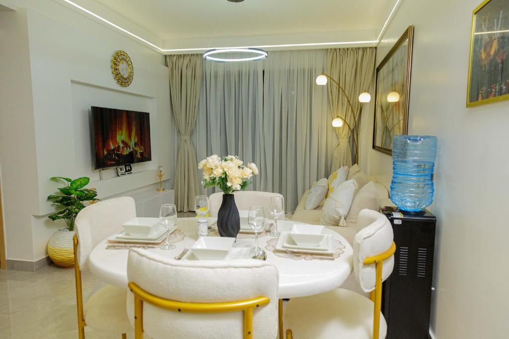 a dining room with a white table and white chairs at Riara One Residency in Gatunga