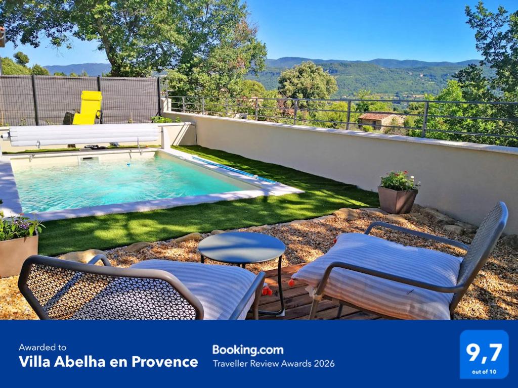 a backyard with a swimming pool and two chairs at Villa Abelha en Provence in Apt