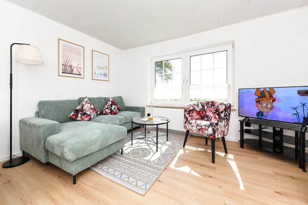 a living room with a couch and a table and a tv at Ferienwohnung Sternstunde in Bensersiel