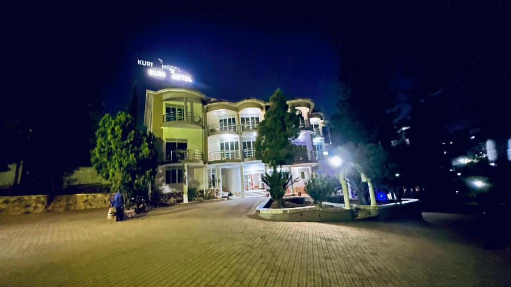 a large building at night with trees in front of it at Kuri hotel Kampala in Kampala