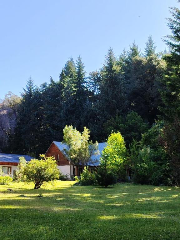 a house in the middle of a yard with trees at Bosque Hostel in Villa Traful
