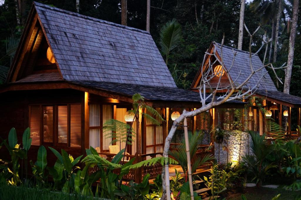 a house in the middle of a forest at night at Uma Cabins by Uma Experience in Penginyahan