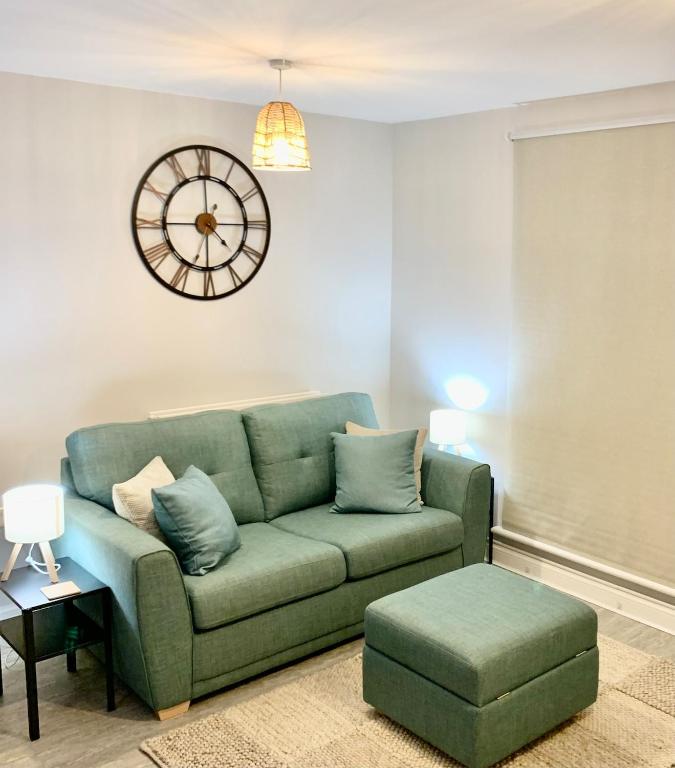 a living room with a green couch and a clock at The Coach House, Cleobury Mortimer in Cleobury Mortimer