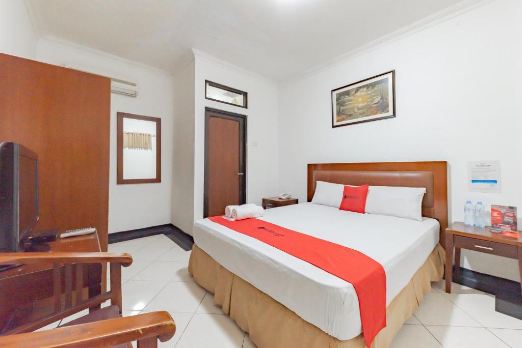 a bedroom with a large bed and a television at RedDoorz Plus at Buah Batu in Bandung