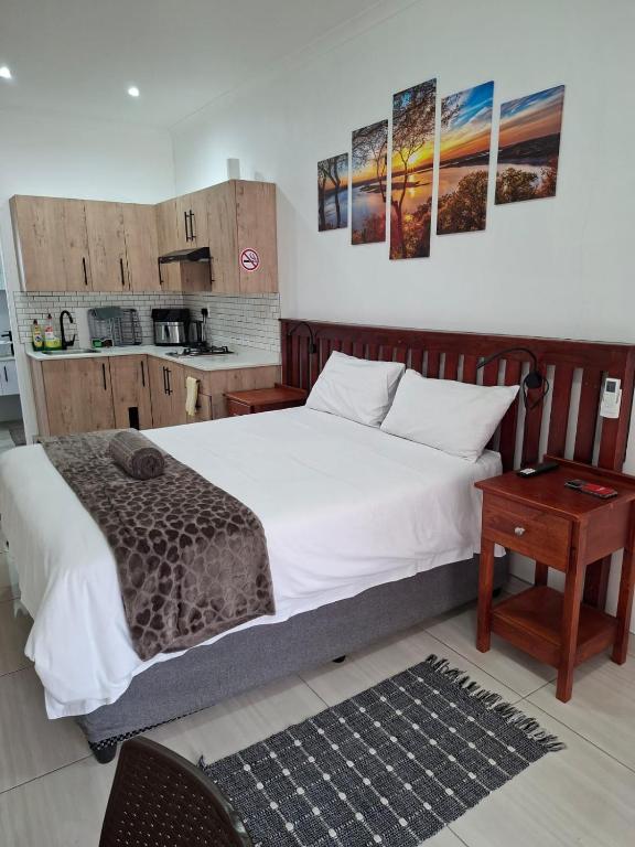 a bedroom with a large bed and a kitchen at Unit 17 Sunbird Self-Catering in Richards Bay