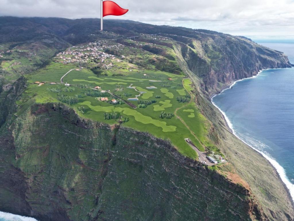 a red flag on top of a mountain next to the ocean at Sunny Sunset House in Ponta do Pargo