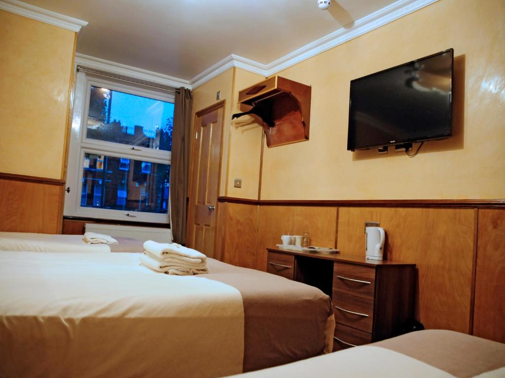 a hotel room with two beds and a flat screen tv at Cricklewood Lodge Hotel in London