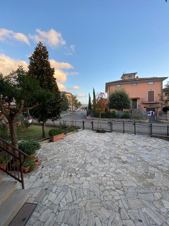 a stone patio with a fence and trees in a park at Casa il Giardino in Castiglion Fiorentino