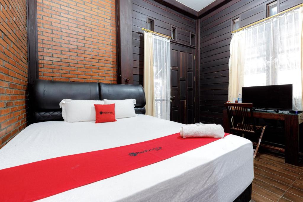 a bedroom with a large bed with a red blanket at RedDoorz @ Cilandak Timur in Jakarta