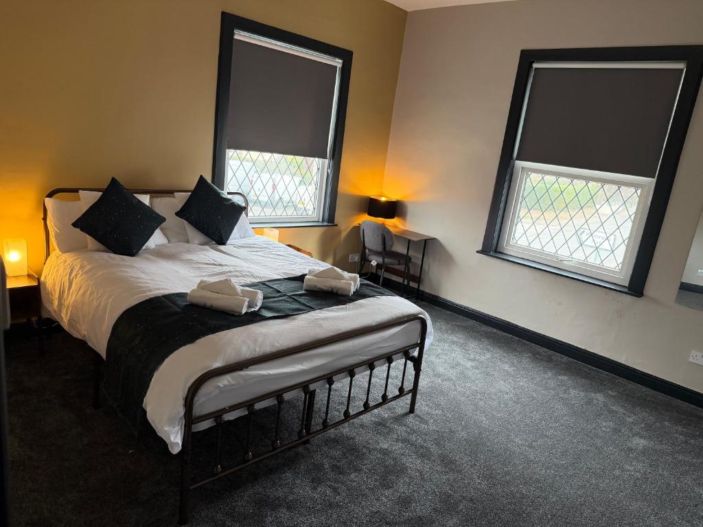 a bedroom with a large bed with two windows at The Victoria Bar & Hotel in Wakefield