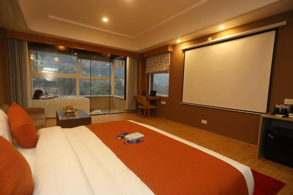 a large bedroom with a large bed and a projection screen at The Udit By West Western - Central Heated and Air Cooled - River View & Roof Top cafe & Bar in Kasol