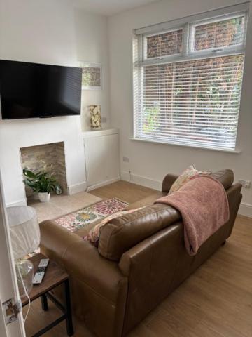 a living room with a brown couch and a fireplace at Stylish Didsbury House in Manchester