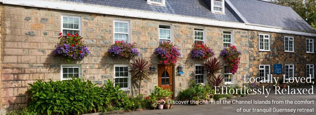a stone building with lots of flowers on it at Le Pommier in Castel