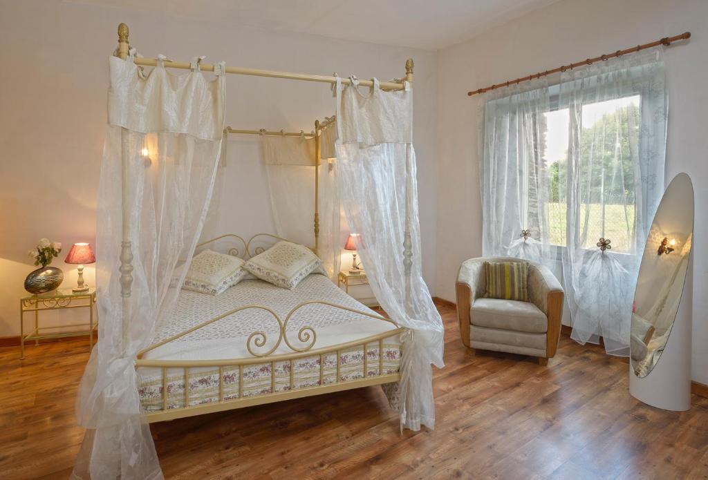 1 dormitorio con cama con dosel y ventana en Domaine de la Cour, en Sainte-Gemme-dʼAndigné