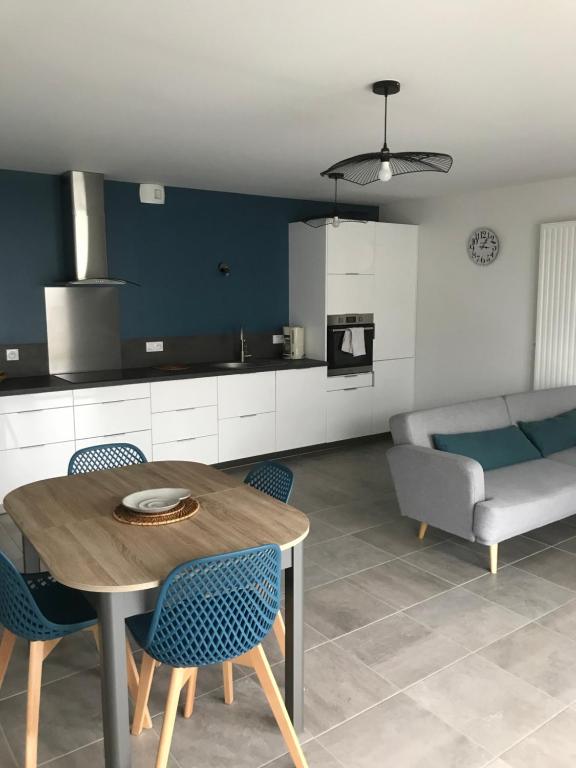 a kitchen and living room with a table and a couch at Appartement récent et à la déco moderne in Damgan