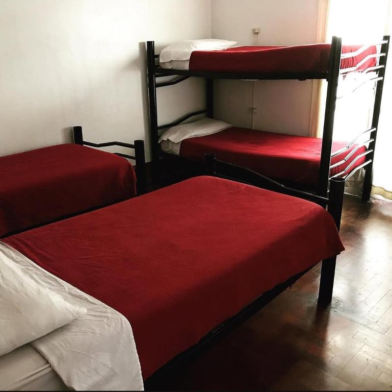 a room with three bunk beds with red sheets at Hostel Lagares in Mendoza