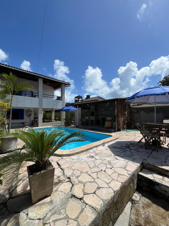 a swimming pool with a patio and a house at Canto da Ita - Próxima a praia com piscina e churrasqueira in Itamaracá