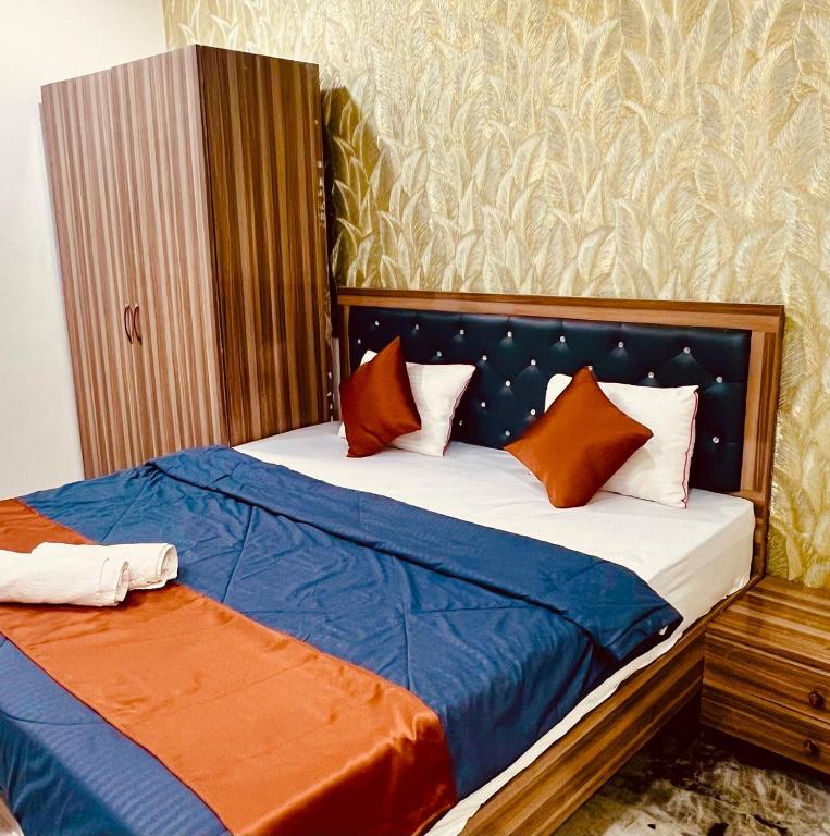 a bed with orange and blue pillows in a room at Hotel Yash Residency in Ulhāsnagar