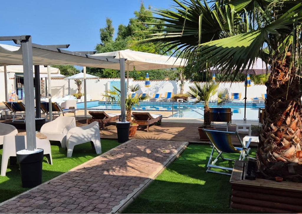 a resort with a pool with chairs and umbrellas at Le Palme Holidays in Palmadula