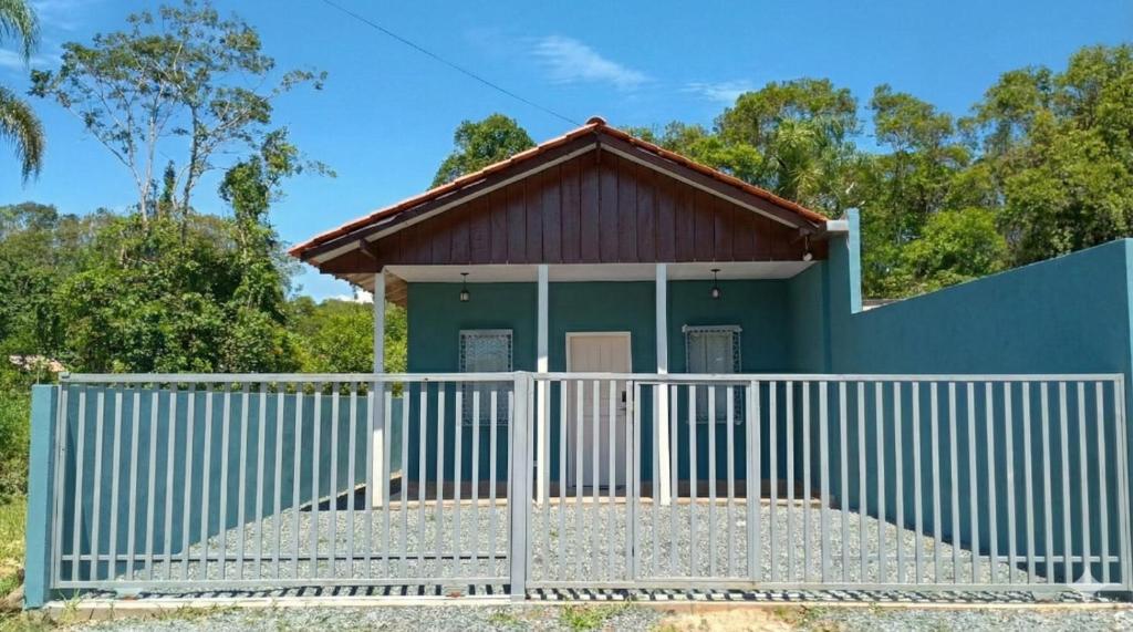 a small green house with a white fence at Excelente casa com isolamento térmico, dois quarto in Itapoa