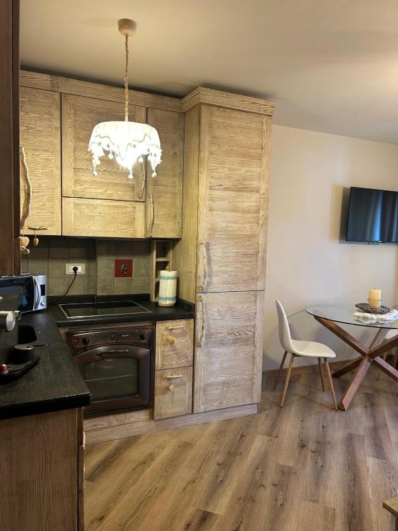 a kitchen with wooden cabinets and a table with a chair at Rifugio nella neve in Sestriere