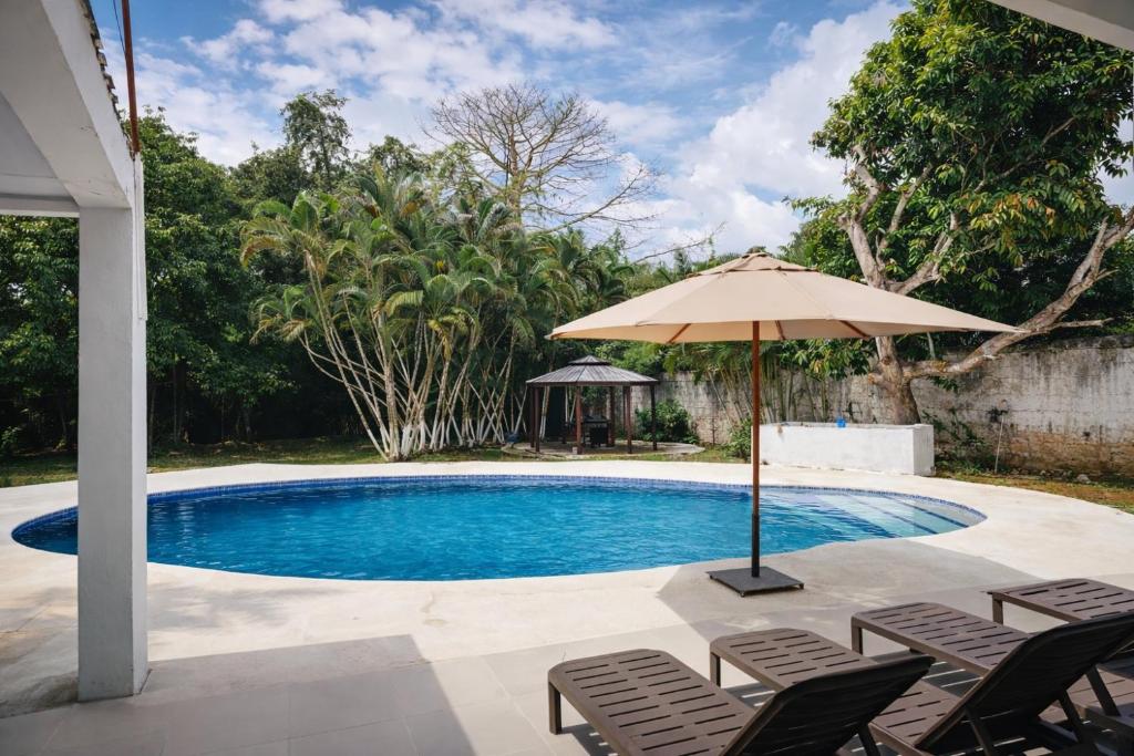 a pool with chairs and an umbrella and a table at Quinta en Melgar piscina BBQ cerca a Piscilago in Melgar