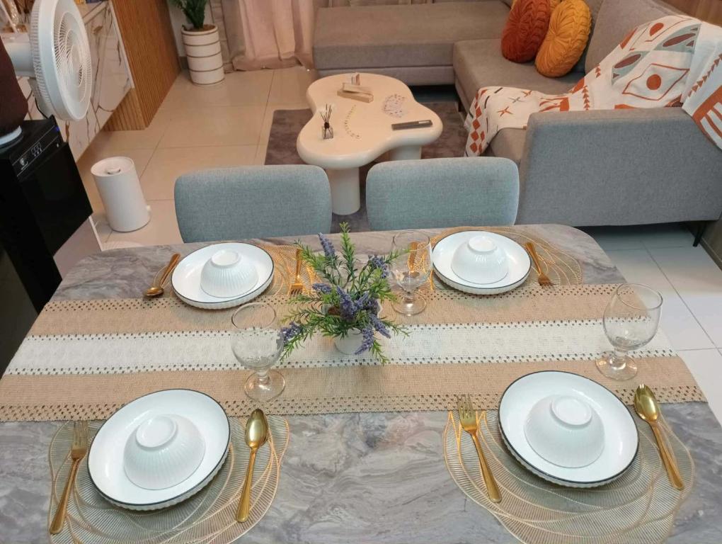 a table with plates and glasses on it in a living room at matthew's cozzy staycation suit in Sampong