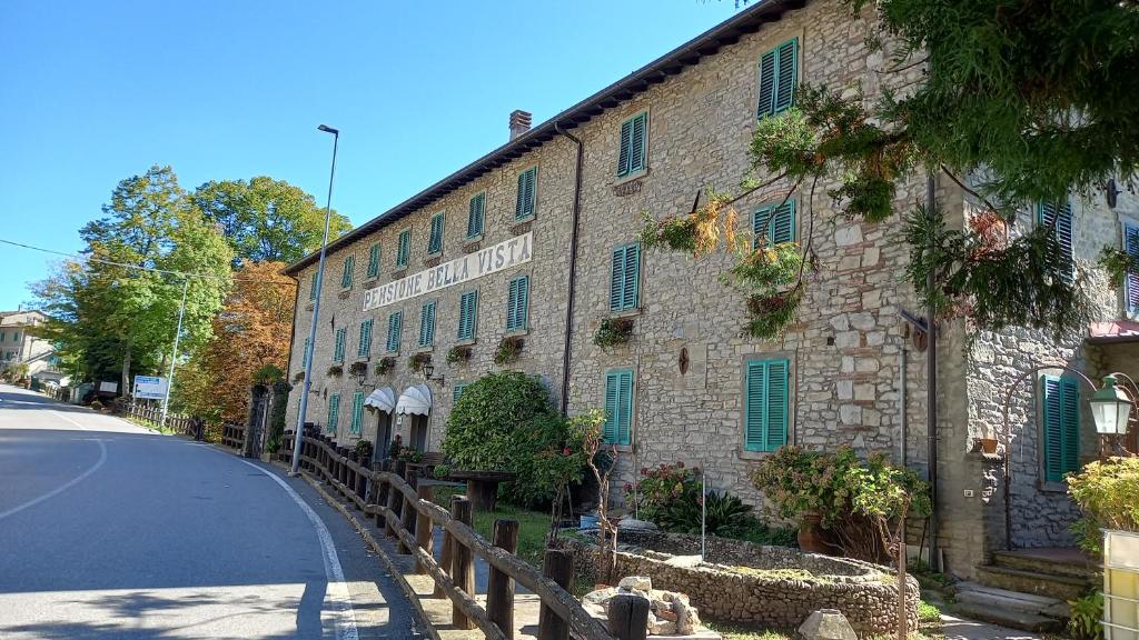 a stone building with green shutters on a street at Bellavista in Badia Prataglia