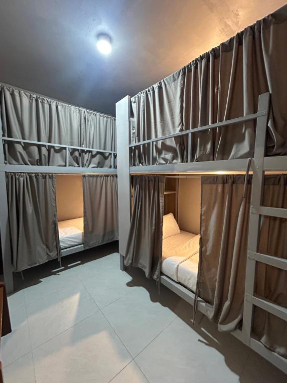 two bunk beds in a room with curtains at Sleep Squad Hostel in El Nido