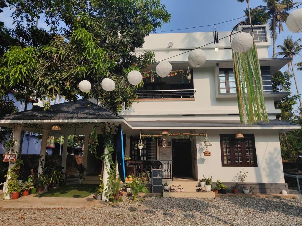 a white house with a tree in front of it at Shamak Homestay Varkala in Varkala