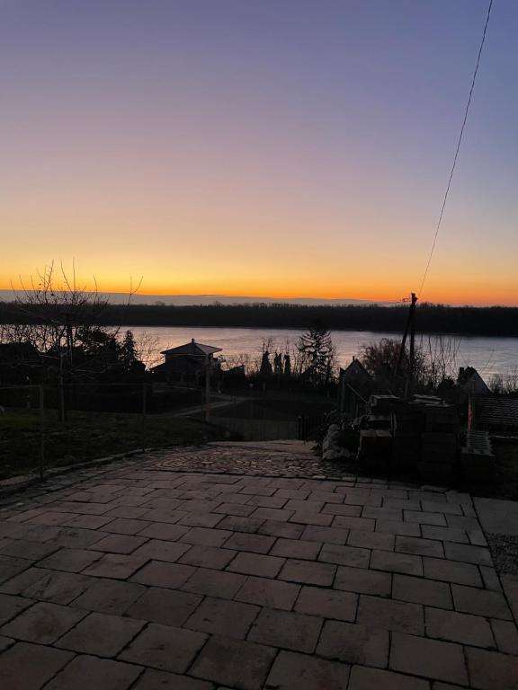 a sunset over a body of water with a brick patio at Duna Panoráma Vendégház in Mohács