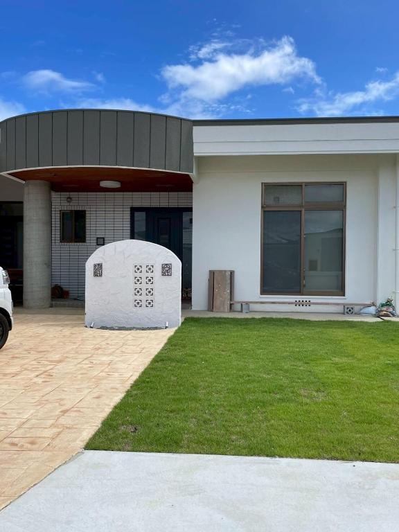 a large white house with a lawn in front of it at Cottage Tasuki in Nakijin