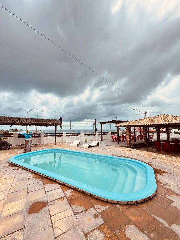 a swimming pool on a patio with a view of the ocean at Pousada beira mar e sol in Tibau