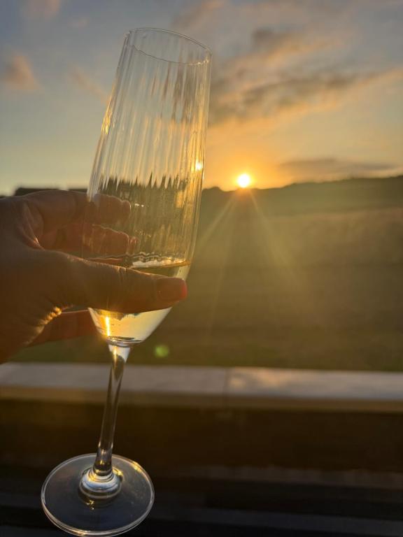 a person holding a wine glass with the sunset in the background at 22 Mountain View in Herolds Bay