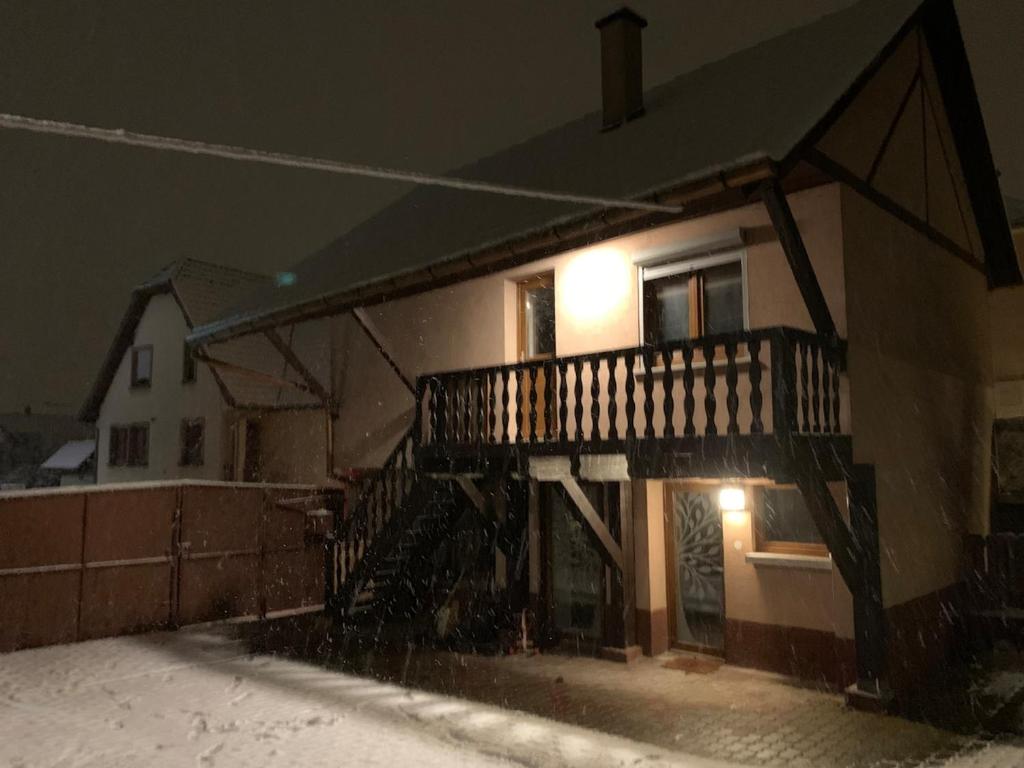 a house with a balcony in the snow at night at Maison atypique Alsacienne in Kintzheim