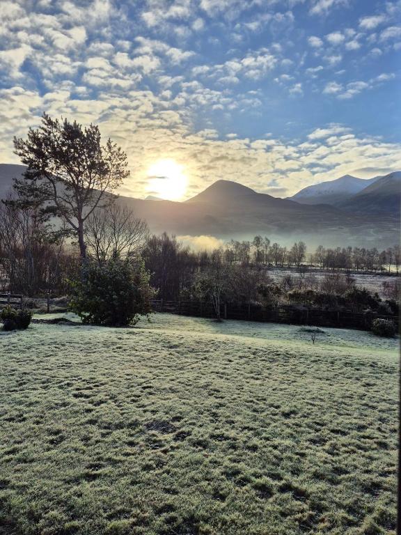 a field with the sun setting in the mountains at Coiseag at Maol Ruadh, Roy Bridge, near Ben Nevis in Roybridge