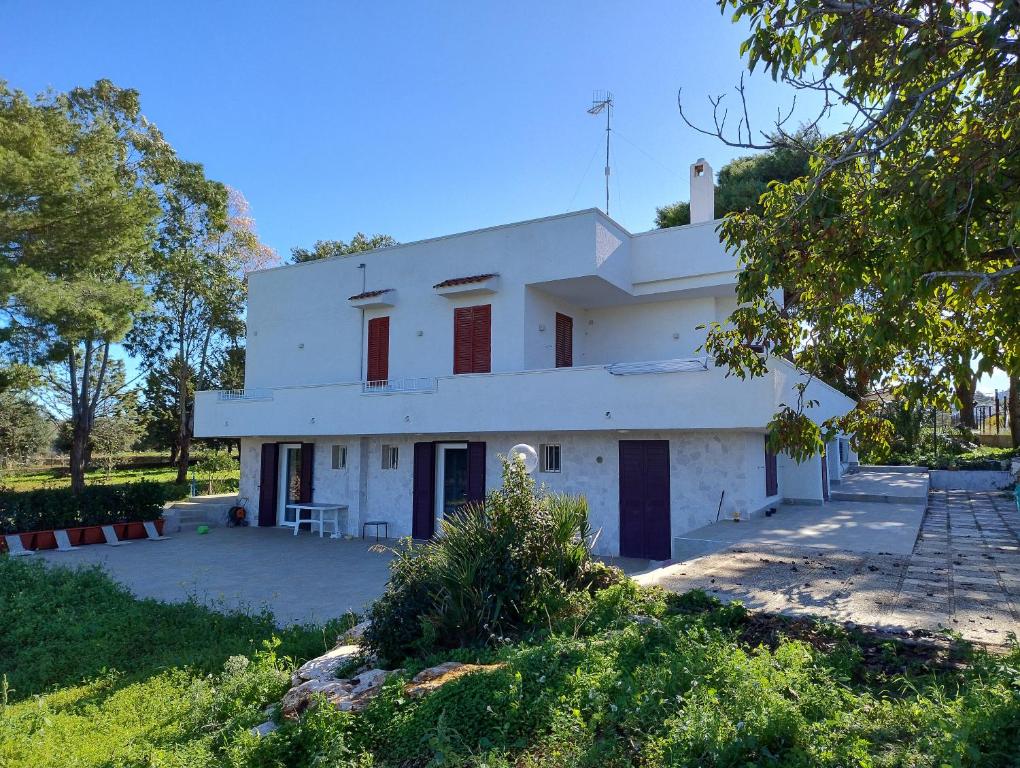 a white house with red windows in a yard at Alba e Colori di Puglia in Conversano